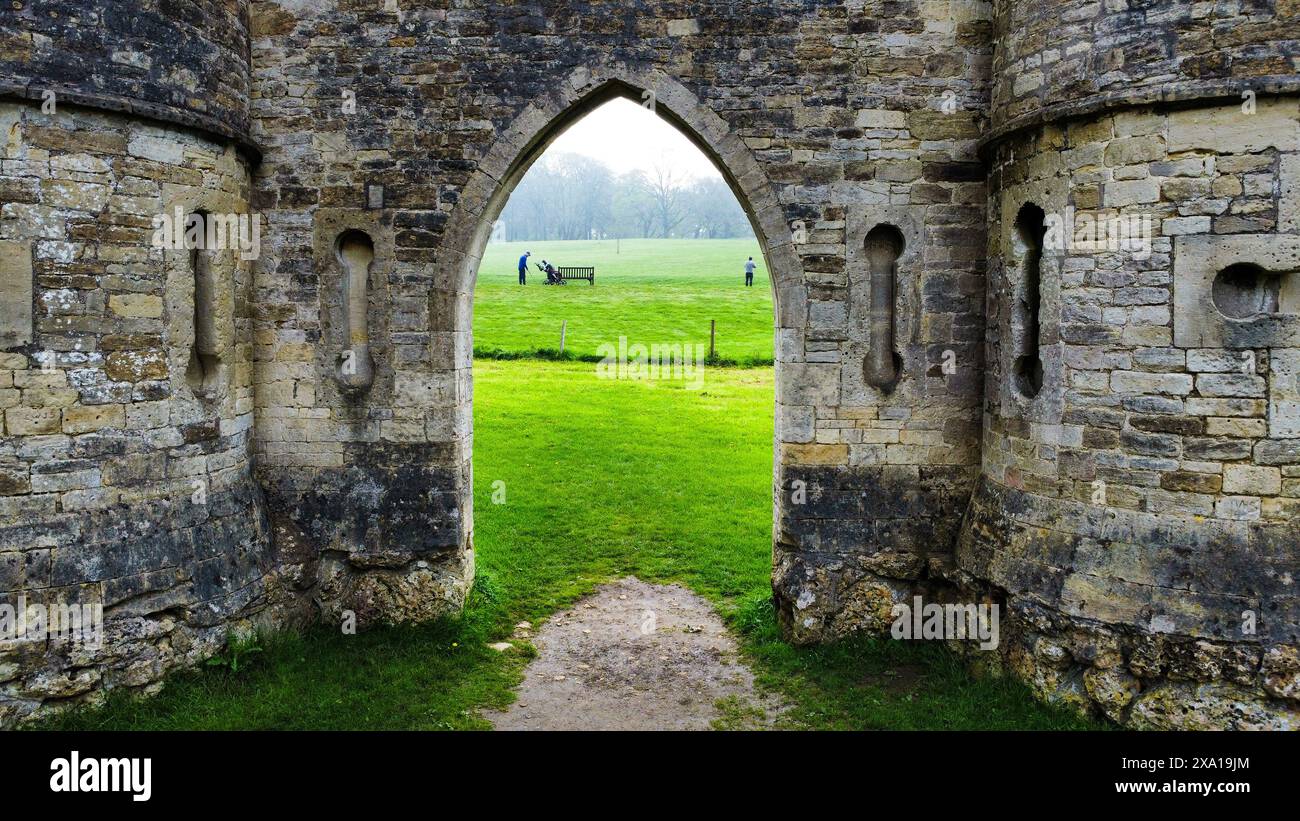 Un gruppo di individui che guardano i lussureggianti campi verdi da un piccolo cortile Foto Stock