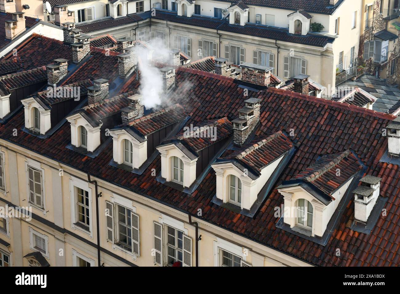 Vista sul tetto di antichi palazzi con camini fumanti nel centro storico di Torino in inverno, Piemonte, Italia Foto Stock