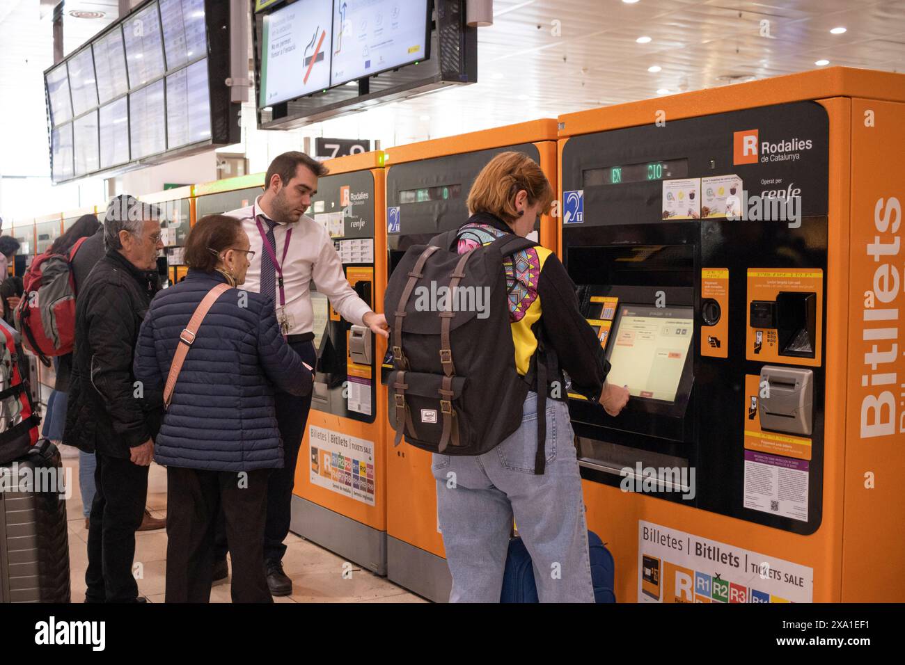 Un gruppo di persone in piedi accanto al distributore automatico di biglietti alla stazione Sants di Barcellona Foto Stock