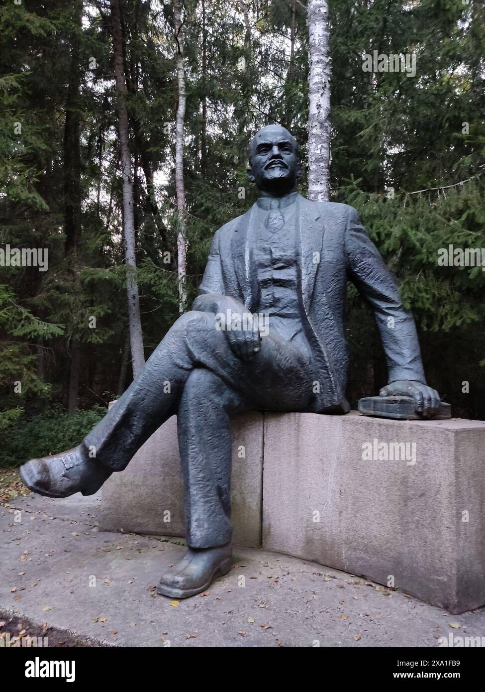 Scultura di un uomo seduto su una base di pietra in una foresta Foto Stock