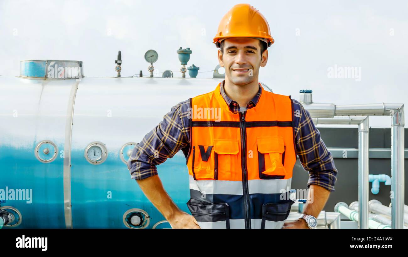 Un uomo in un giubbotto di sicurezza accanto a un serbatoio dell'olio. Foto Stock