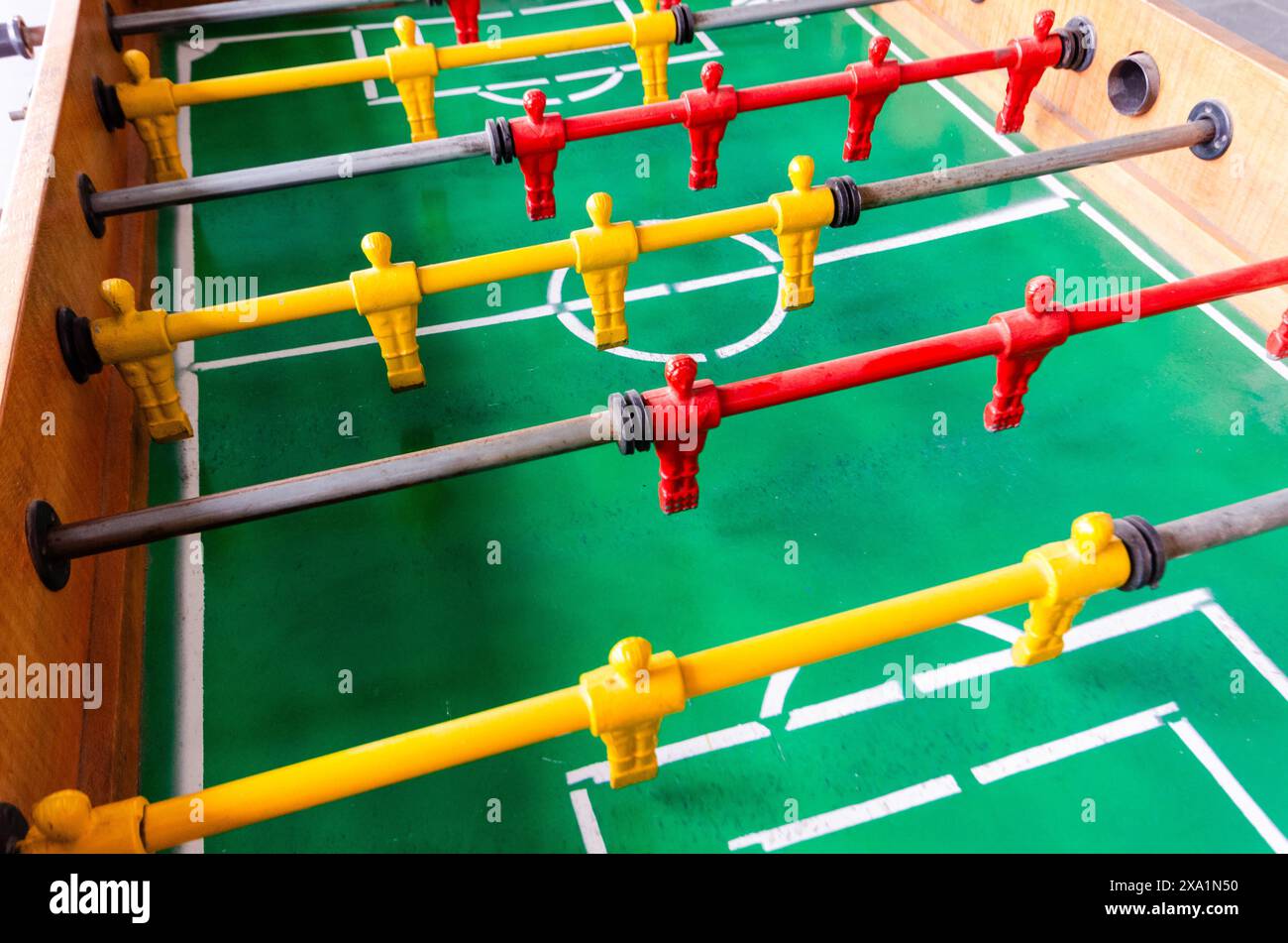 Tavolo da calcio verde con manici rossi e palla gialla Foto Stock