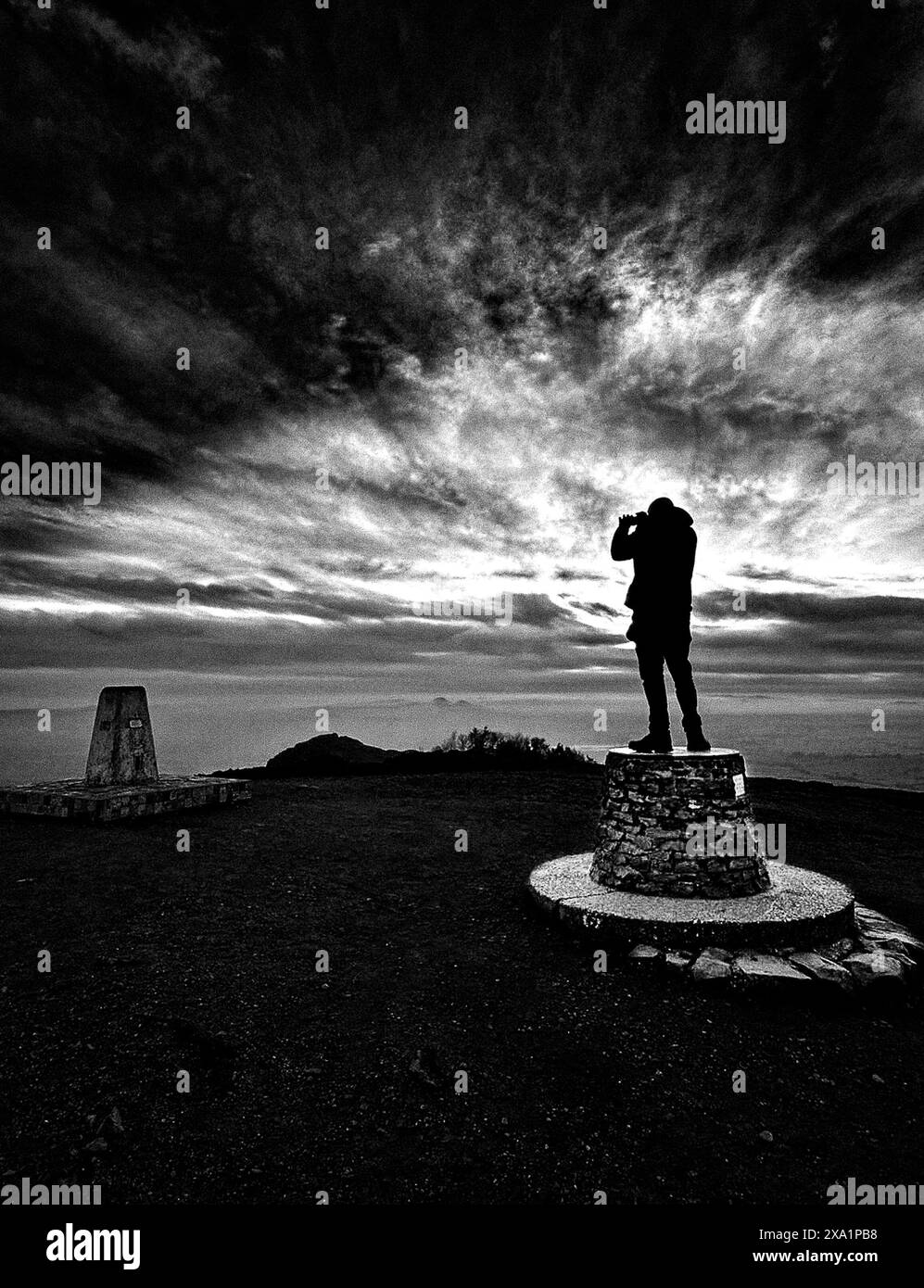 Un uomo con un ombrello sul gradino vicino al faro Foto Stock