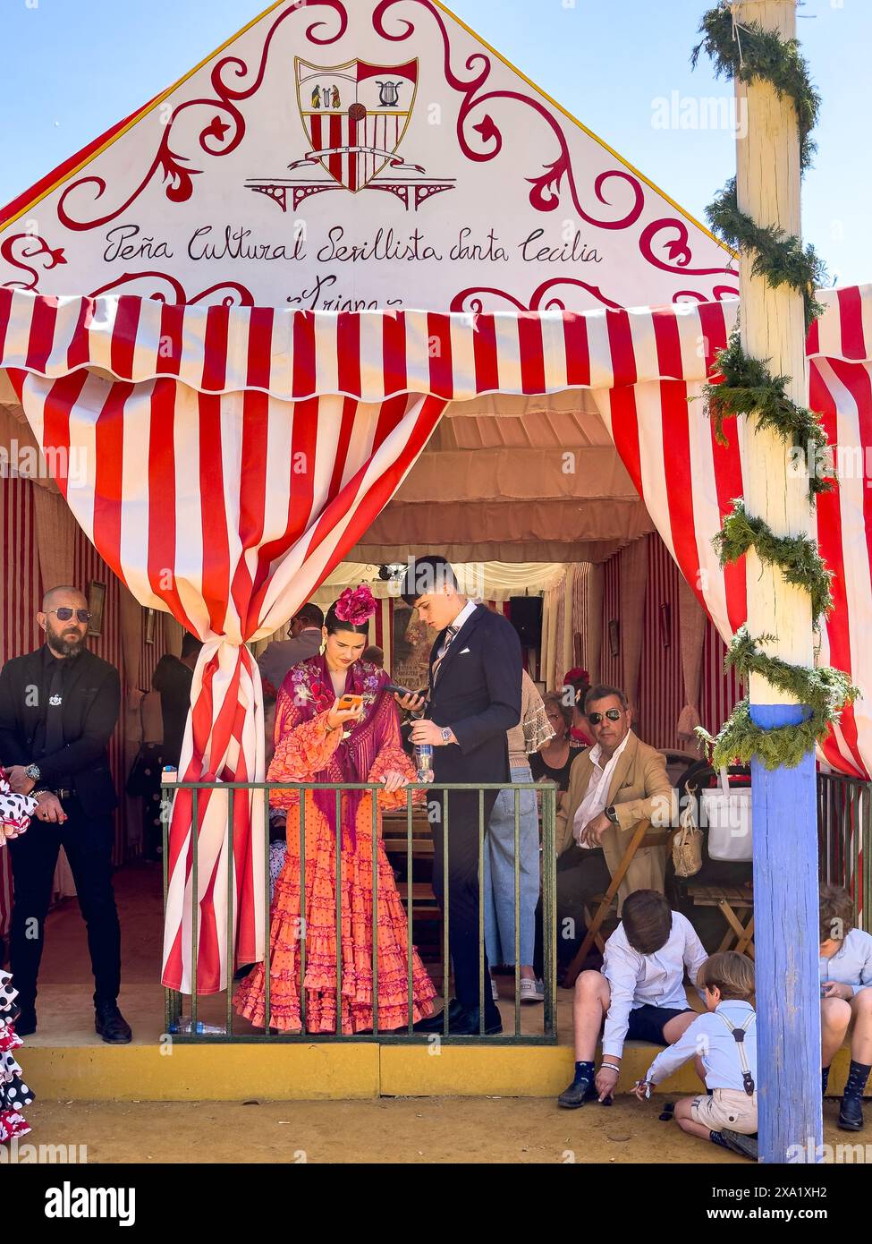 Una coppia in abito flamenco e costume mattutino che controllano il telefono a Feira de Abril a Siviglia, Spagna Foto Stock