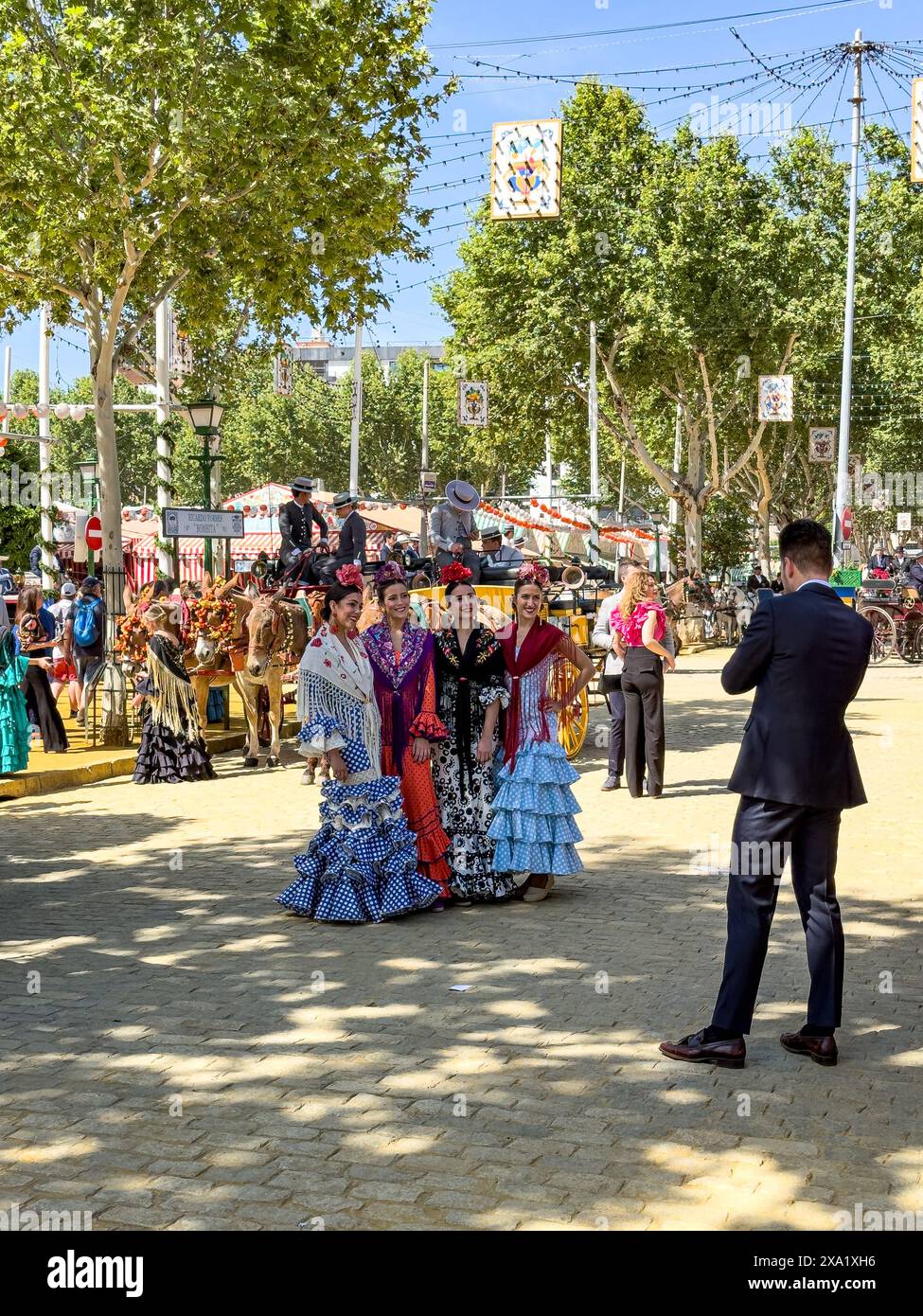 Un uomo che scatta una foto di un gruppo di donne in abiti di flamenco a Feira de Abril a Siviglia in Spagna Foto Stock