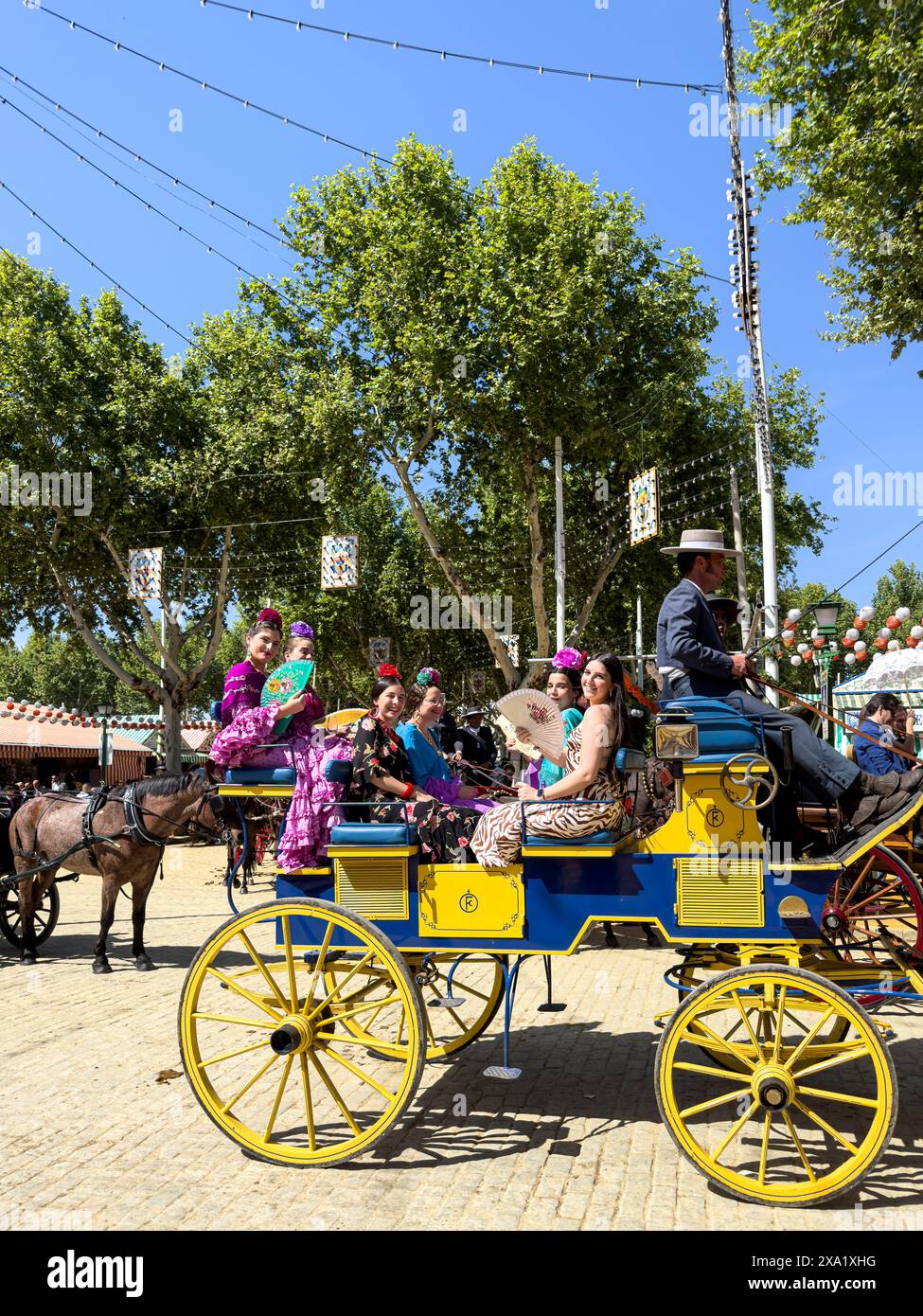 Donne in abiti tradizionali di flamenco su una carrozza trainata da cavalli alla Feria de Abril, nota anche come la Fiera di Siviglia Foto Stock