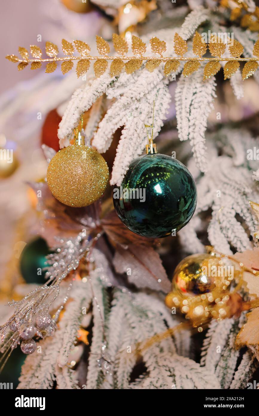 Un albero di Natale splendidamente decorato con ornamenti dorati, luci e decorazioni sospese Foto Stock