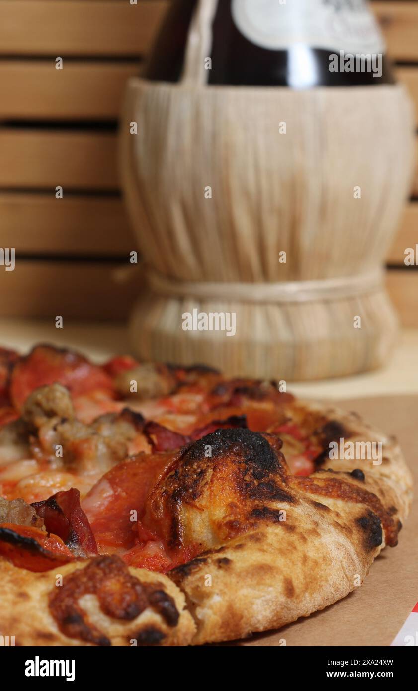 Una pizza appena sfornata su un tavolo con pomodori Foto Stock