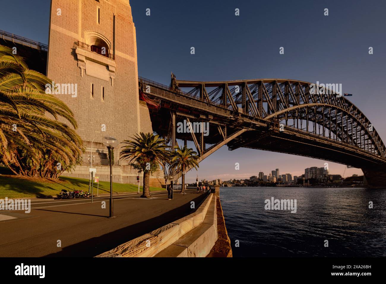 Un ponte attraversa un corpo d'acqua con edifici distanti sotto un grattacielo Foto Stock