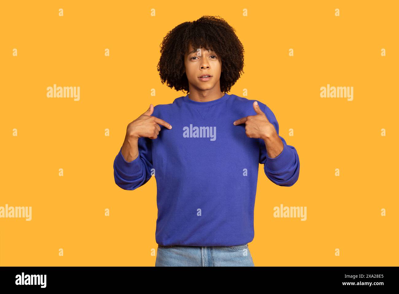 Young Man in Blue Pullover che punta a se stesso contro Yellow Foto Stock