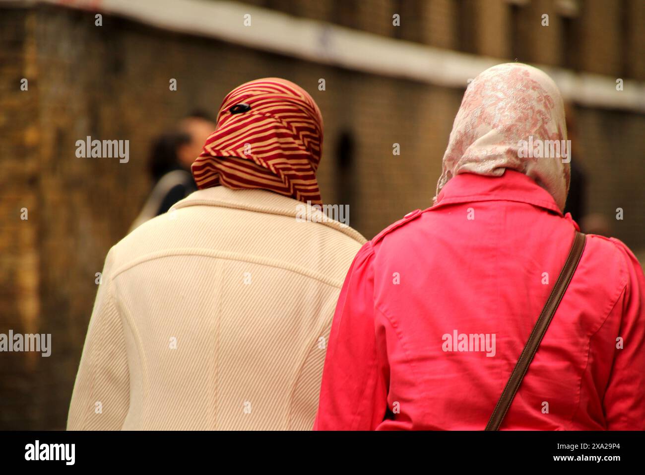 Le donne islamiche passeggiano attraverso una strada urbana trafficata Foto Stock