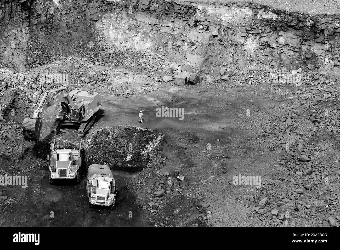 Una scala di grigi di camion che lavorano in una miniera Foto Stock