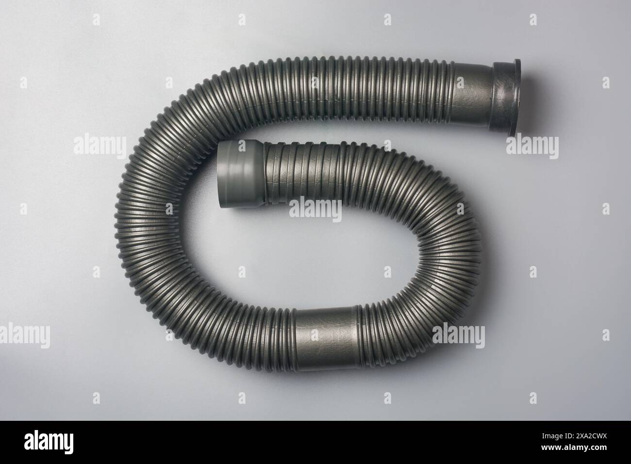 tubo flessibile ondulato o tubo flessibile, tubo flessibile in plastica o pvc sfondo grigio isolato, utilizzato in sistemi idraulici per l'alimentazione e il drenaggio dell'acqua Foto Stock