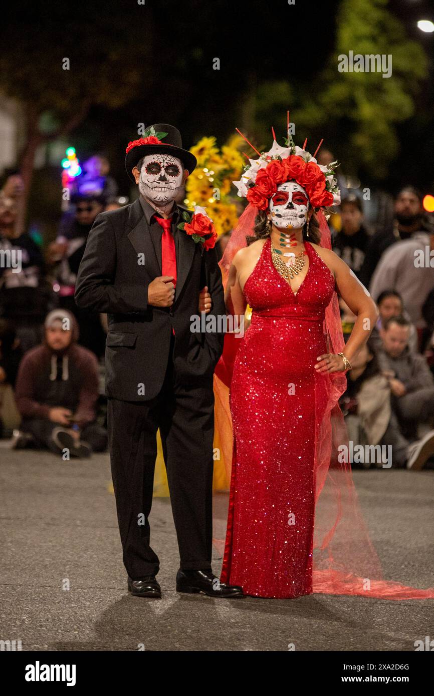 Una coppia in costume è composta come testa di morte o calaveras in una sfilata di Halloween notturna ad Anaheim, CA. Sono utilizzati nella celebrazione messicana o Foto Stock