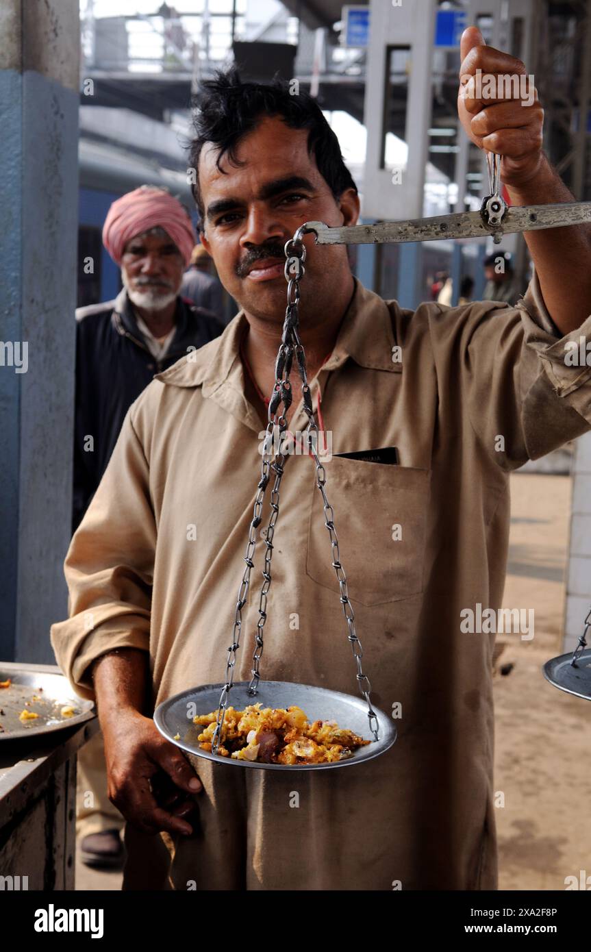 Un venditore di snack che vende Pakoras (uno spuntino indiano) nella stazione ferroviaria di Amritsar. Punjab, India. Foto Stock