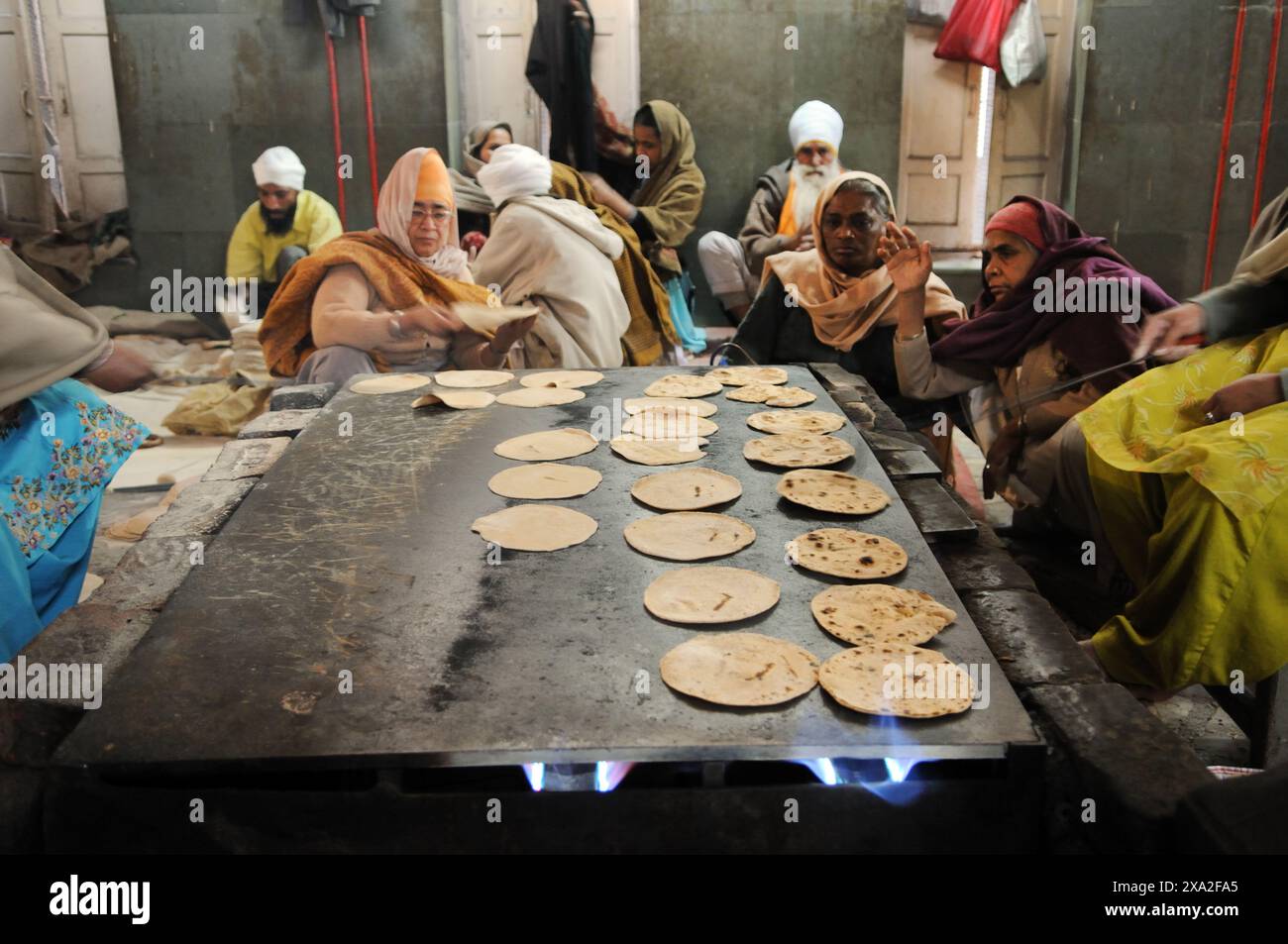 I volontari cucinano chapatis nella cucina del tempio d'Oro, Amritsar, India. Foto Stock