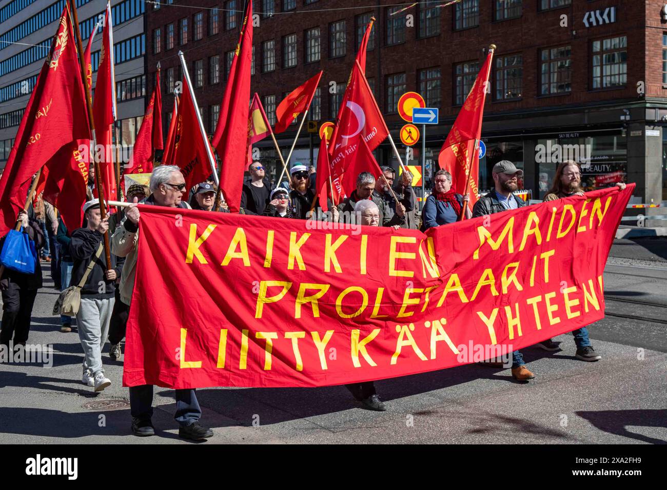 Kaikkien proletaarit liittykää yhteen! Comunisti che portano un grande striscione rosso alla marcia del Labor Day nel quartiere Hakaniemi di Helsinki, Finlandia. Foto Stock