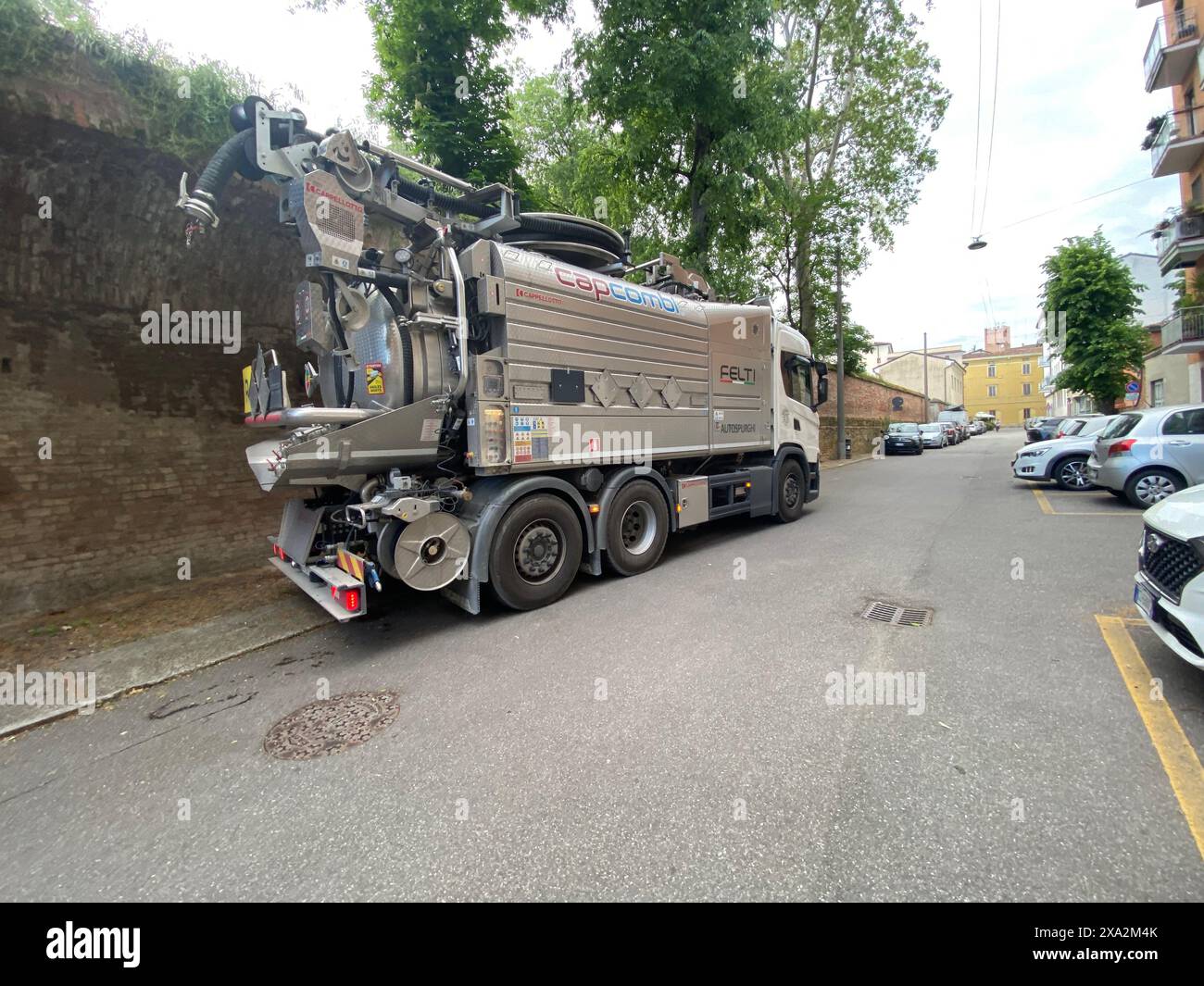 Lombardia, Italia - 2 maggio 2024 il camion di aspirazione delle acque reflue sta rimuovendo le acque reflue e i fanghi da un pozzetto di una strada cittadina, garantendo un'adeguata igiene e Foto Stock
