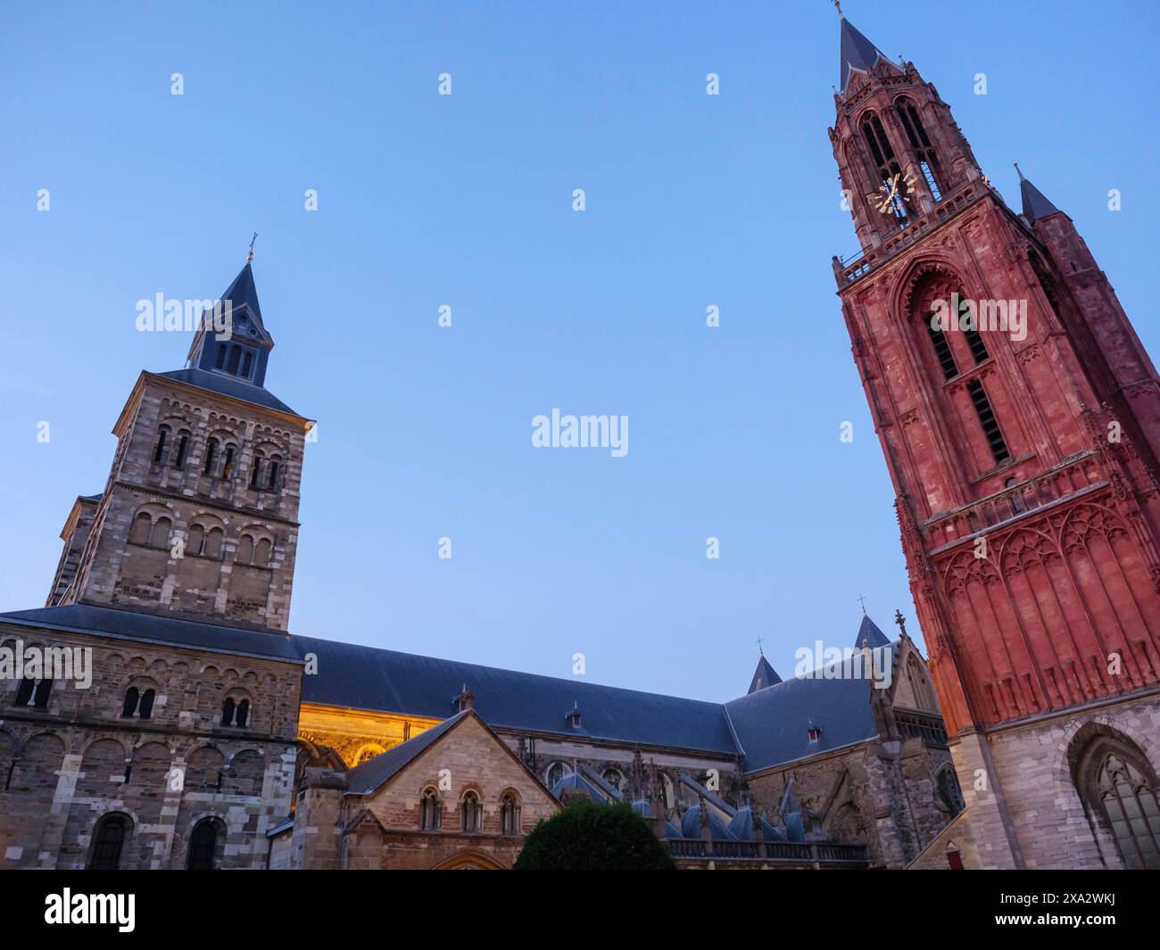 Torri ed edifici della chiesa durante l'ora blu, la torre rossa forma un contrasto, Maastricht, Paesi Bassi Foto Stock