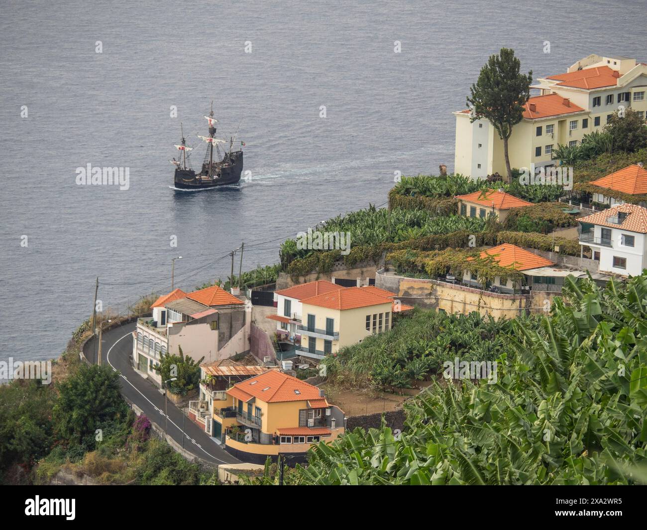 Città costiera con case su una collina e una nave sull'acqua blu, Madeira, Portogallo Foto Stock