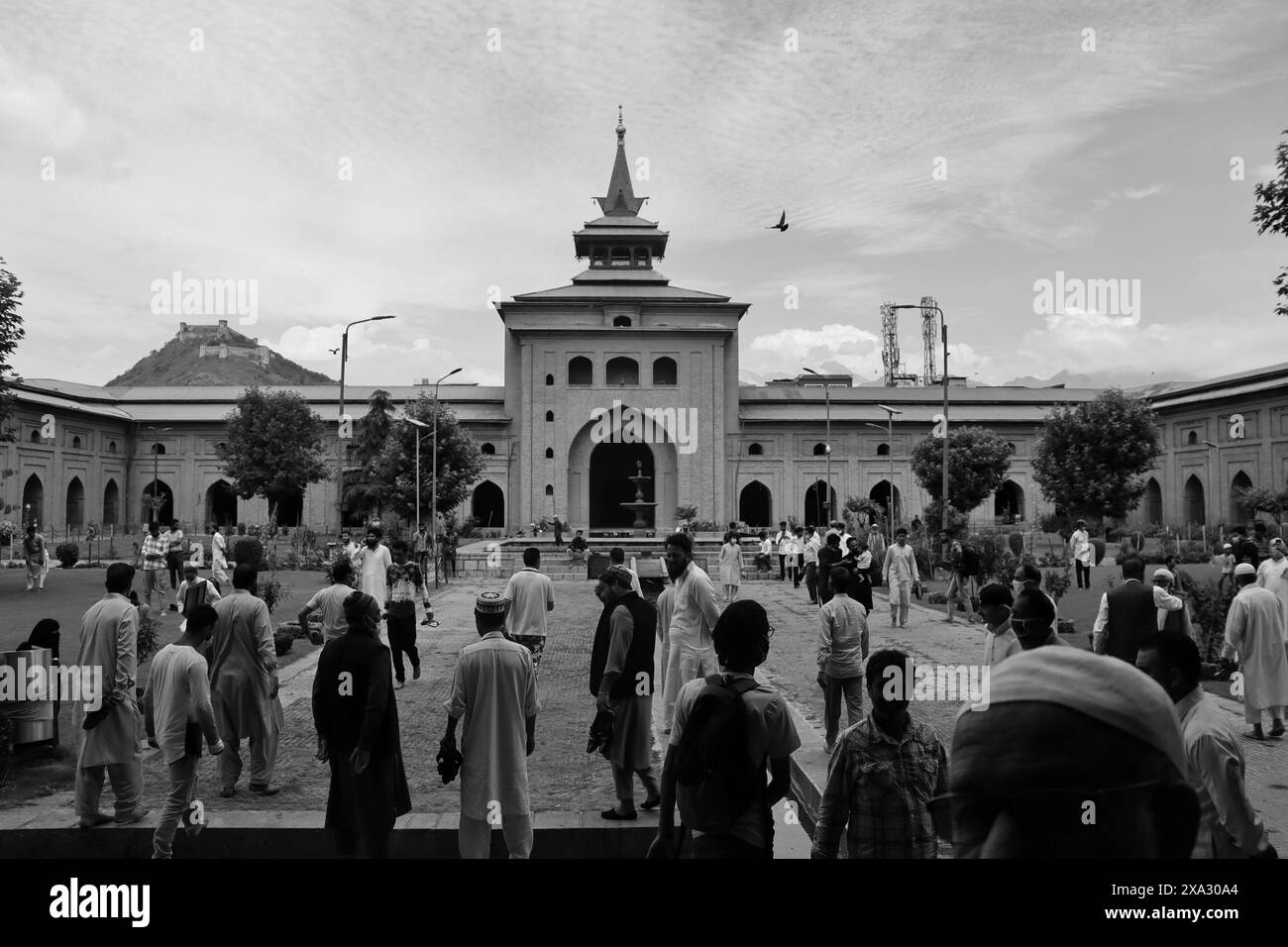 Immagine in bianco e nero di persone nel cortile di una grande moschea con architettura storica, Srinagar, Jammu e Kashmir, India Foto Stock