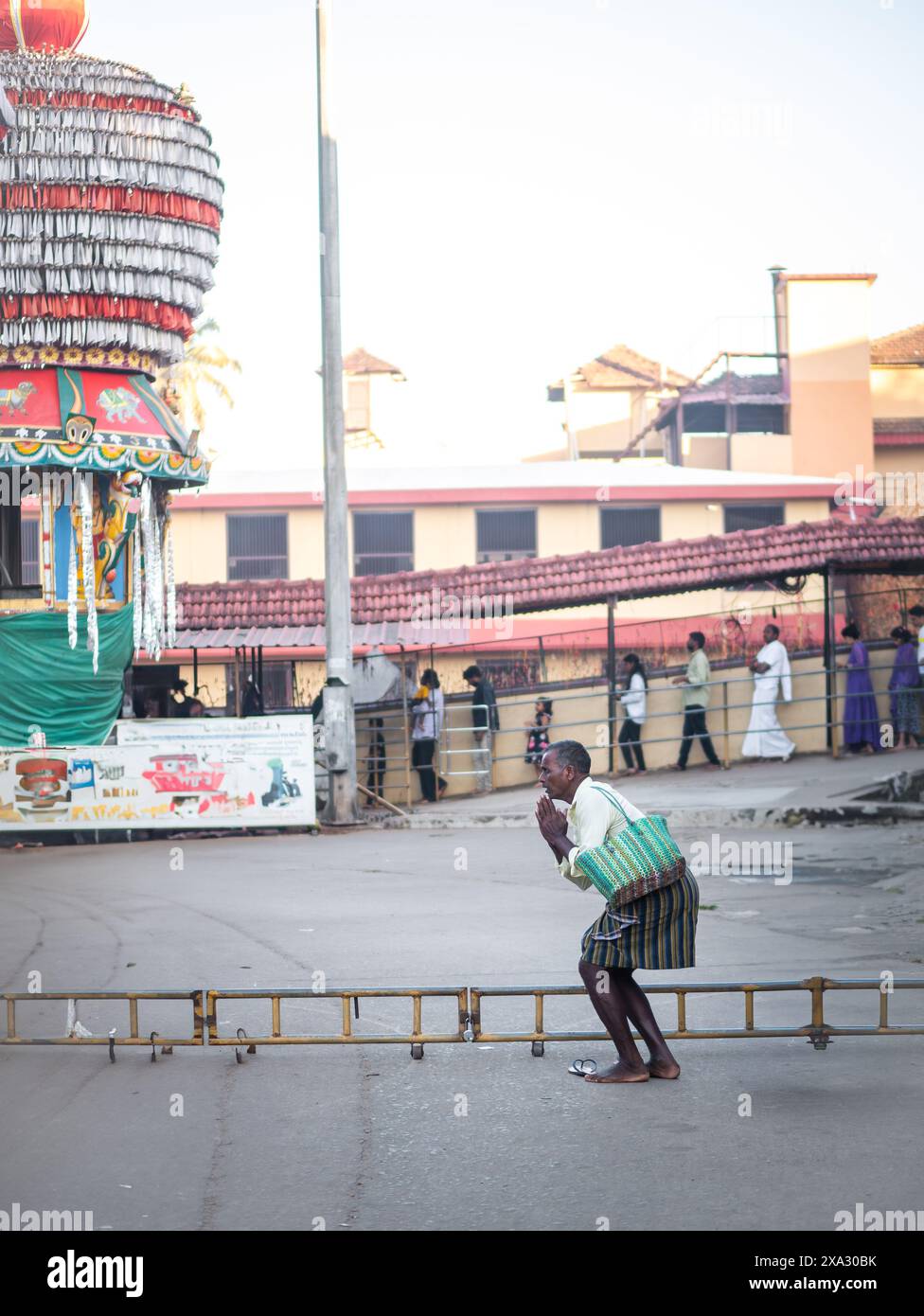 Udupi, INDIA - 27 dicembre 2024: Uomo indiano che indossa abiti etnici che offre preghiere fuori dal tempio Foto Stock