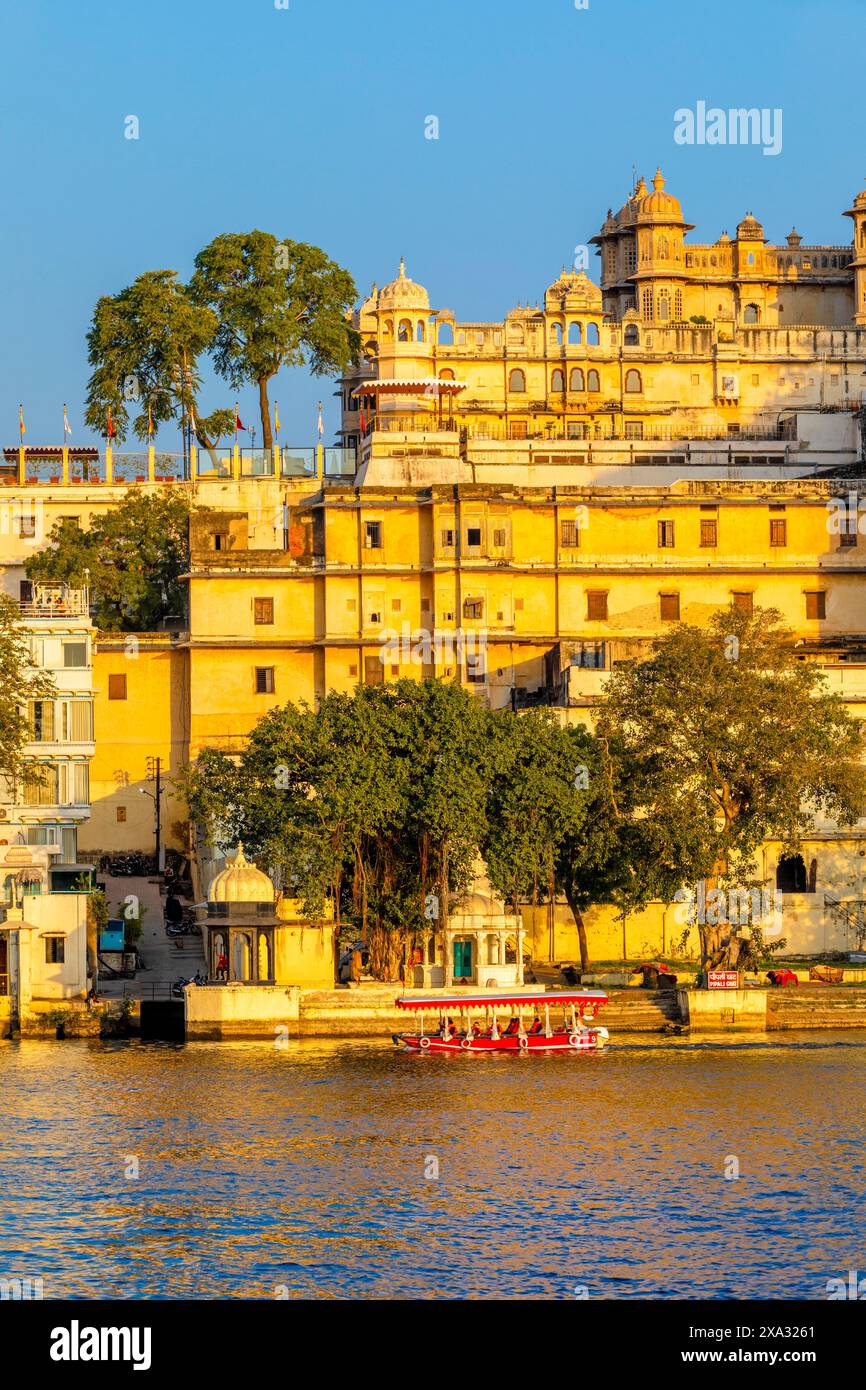 Barca turistica sul lago Pichola con il Palazzo della città sullo sfondo, Udaipur, Rajasthan, India, Asia meridionale. Foto Stock