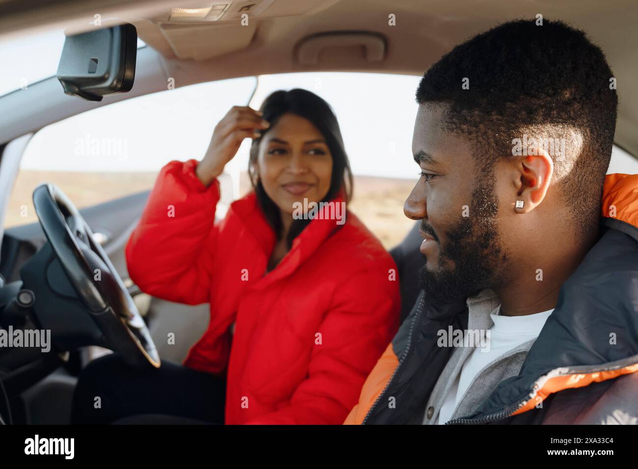 Bella felice giovane coppia amorevole che si tiene per mano e sorride mentre si siede nella loro prima auto. Acquista la tua prima auto concept Foto Stock