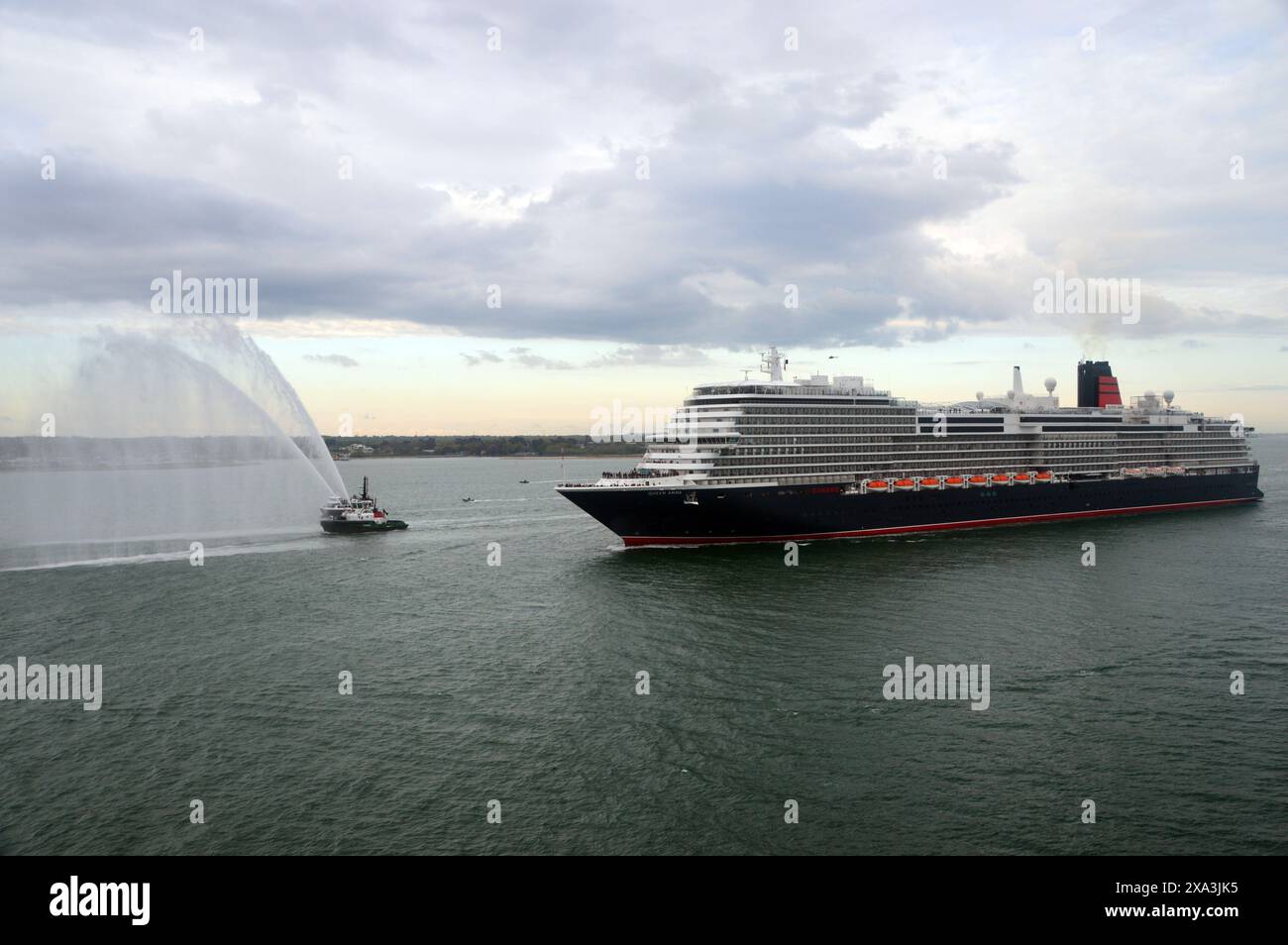 Queen Anne, la nuova nave da crociera di lusso gestita da Cunard, che naviga sul Solent vicino a Southampton con una guardia d'onore da un Tug Boat antincendio. Foto Stock