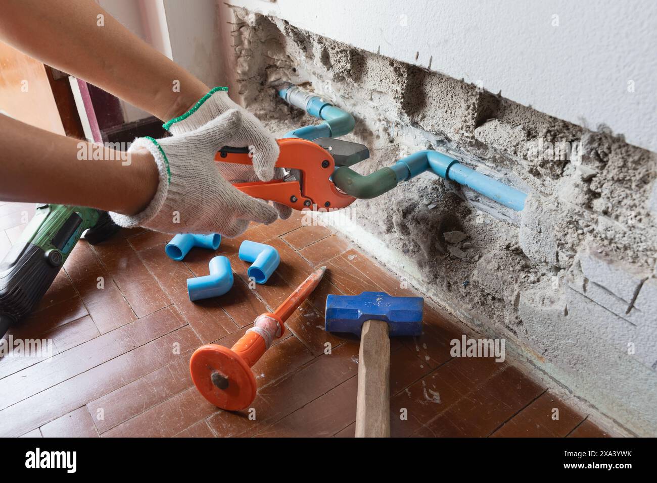 L'idraulico deve aprire una parete per accedere a un tubo rotto. Foto Stock