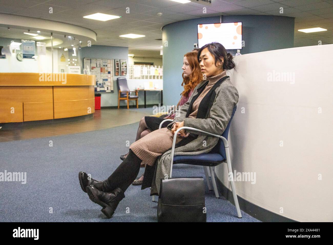 Due persone sedute in una sala d'attesa di uno studio medico Foto Stock