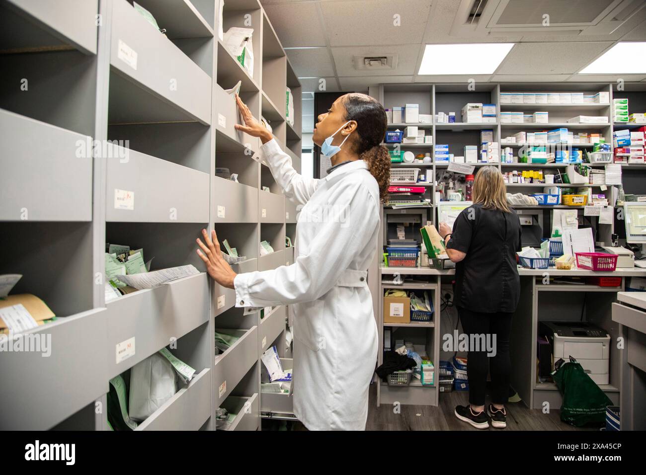 Farmacisti che lavorano in una stanza di deposito dei farmaci in uno studio medico, Regno Unito Foto Stock