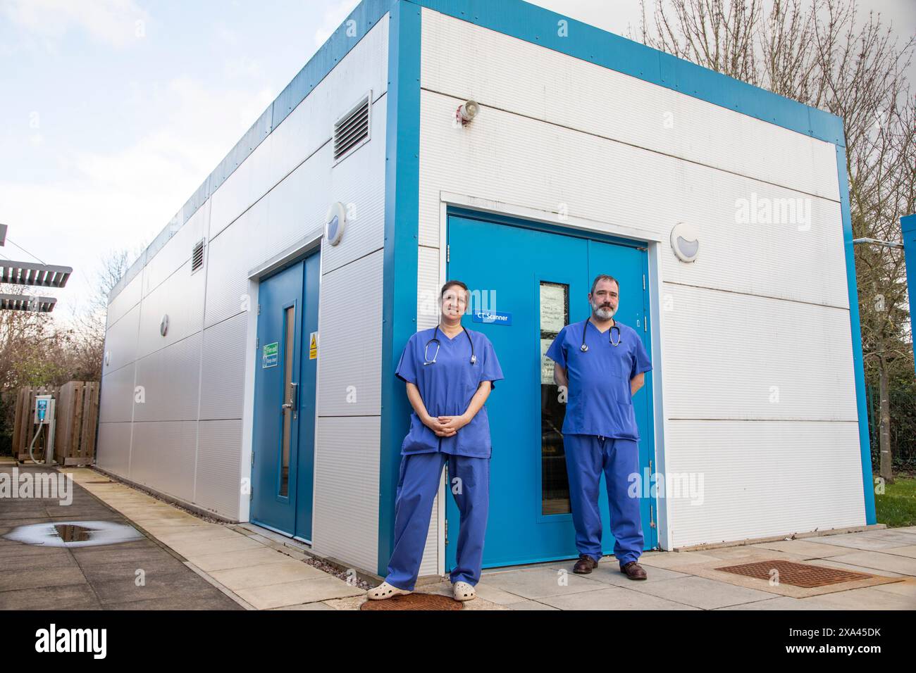 Personale medico in piedi fuori da una clinica di fronte a uno scanner TC Foto Stock