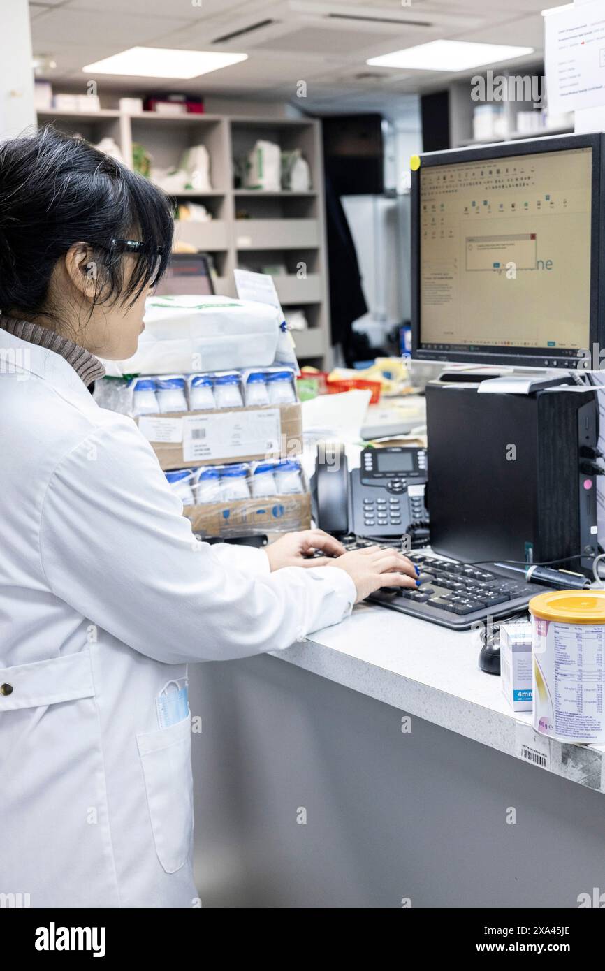 Lo scienziato lavora in un computer in un laboratorio e nell'area di spedizione di una pratica medica Foto Stock