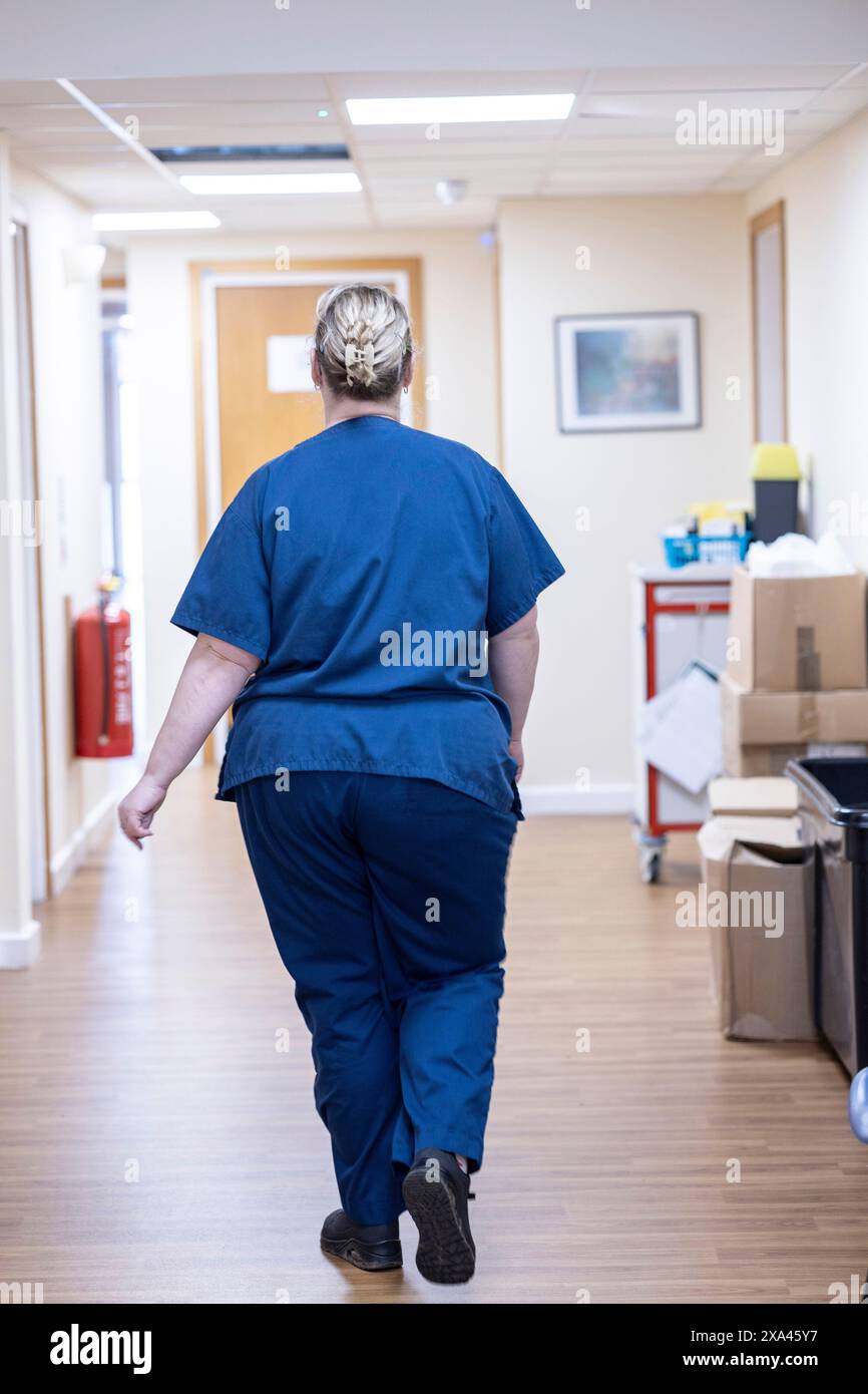 Medico che cammina lungo un corridoio dell'ospedale Foto Stock