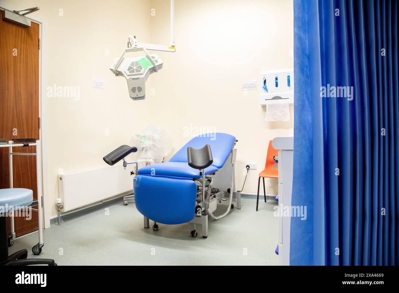 Una sala per visite mediche ben attrezzata con sedia blu. Foto Stock