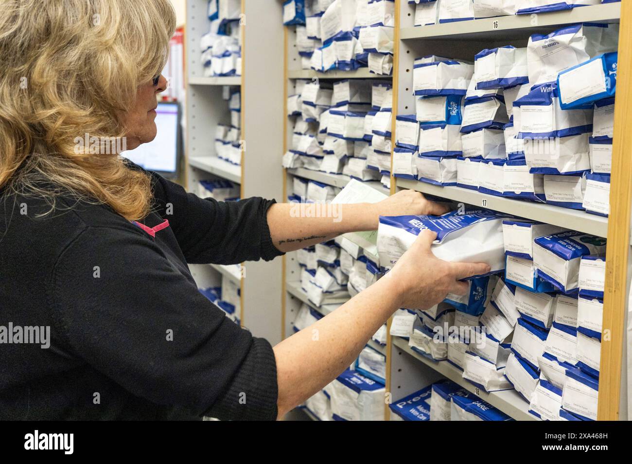 Donna che rifornisce gli scaffali della farmacia con farmaci. Foto Stock