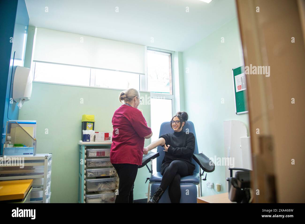 Infermiere che esegue l'esame del sangue al paziente in clinica. Foto Stock