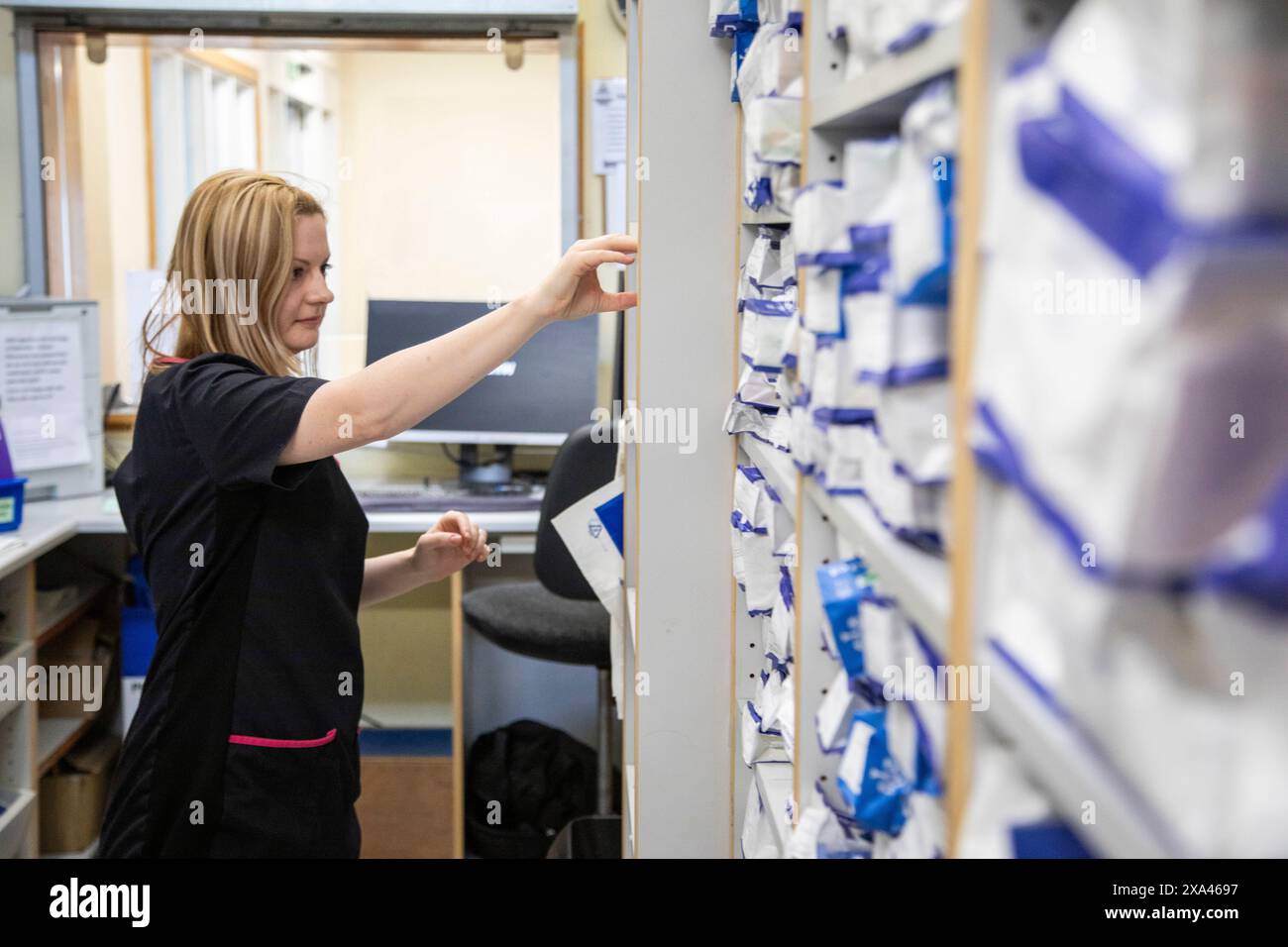 Infermiere che recupera un file da un sistema di archiviazione ospedaliero Foto Stock