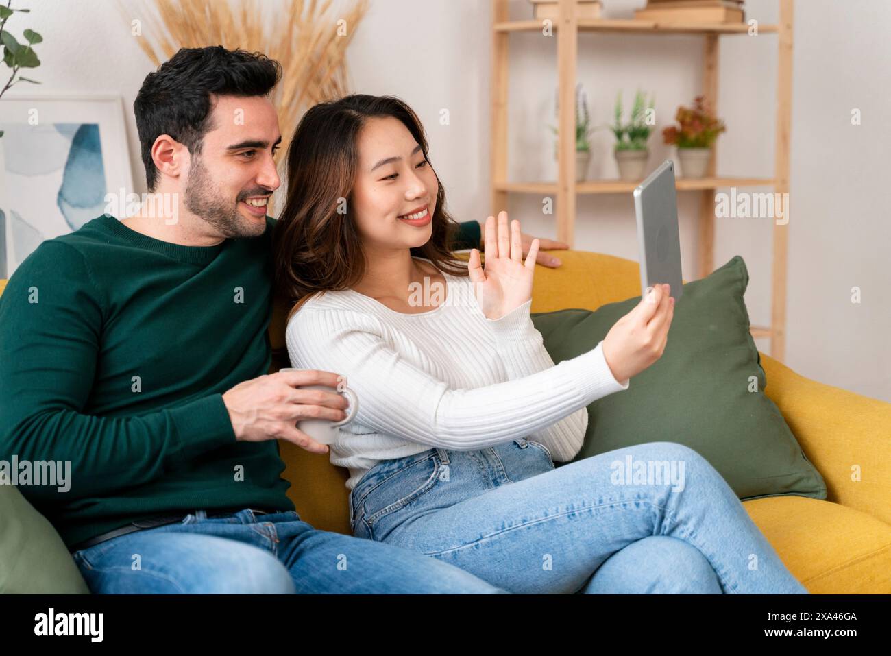 Coppia che fa un selfie su un divano giallo. Foto Stock