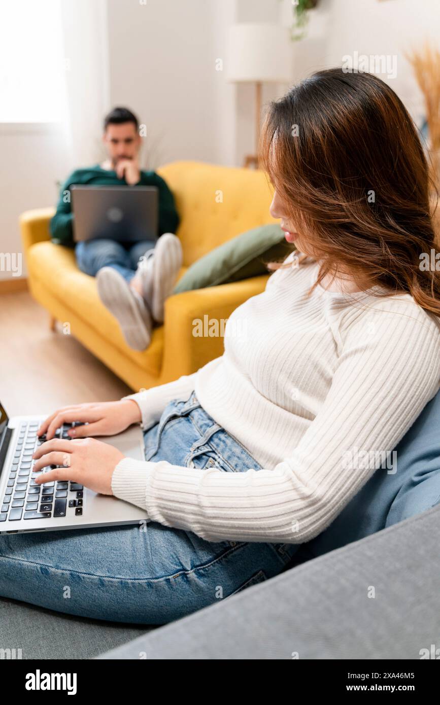 Donna che lavora su un notebook con un uomo in background Foto Stock