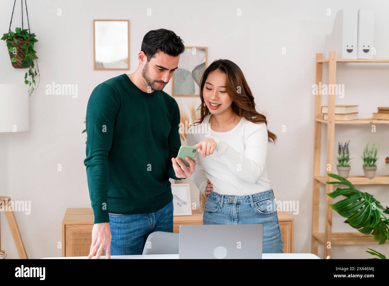 Due persone che guardano uno smartphone insieme in un ufficio moderno Foto Stock