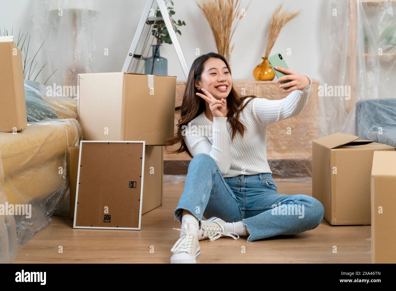 Donna che si sta facendo un selfie in mezzo a scatole in movimento. Foto Stock