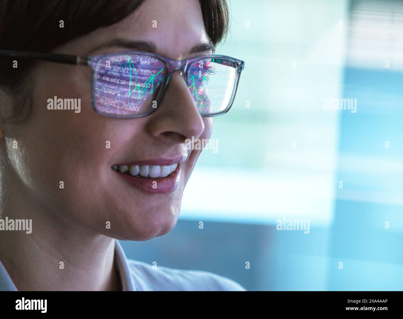 Primo piano di una donna sorridente che indossa occhiali che riflettono grafica colorata per la visualizzazione dei dati. Foto Stock