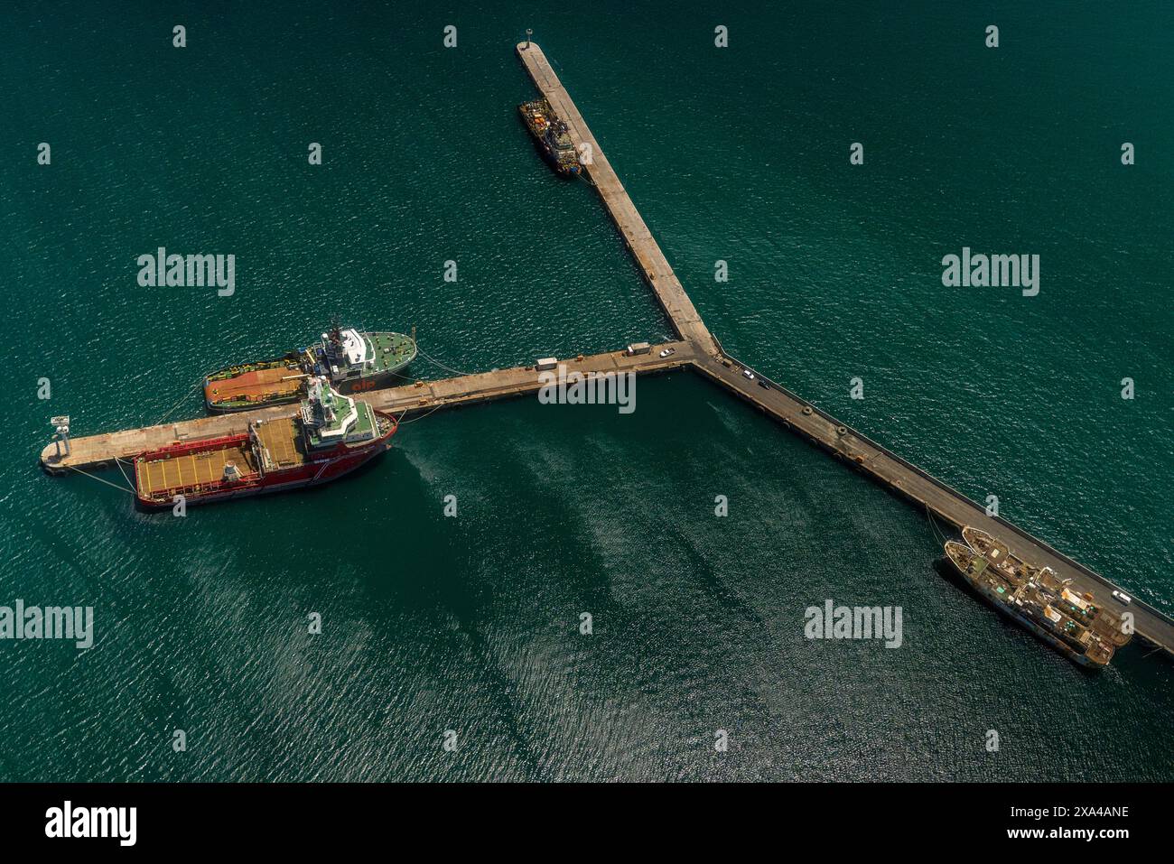 Veduta aerea di un molo con due navi attraccate su entrambi i lati, con una piccola struttura all'estremità e container sul molo. Foto Stock