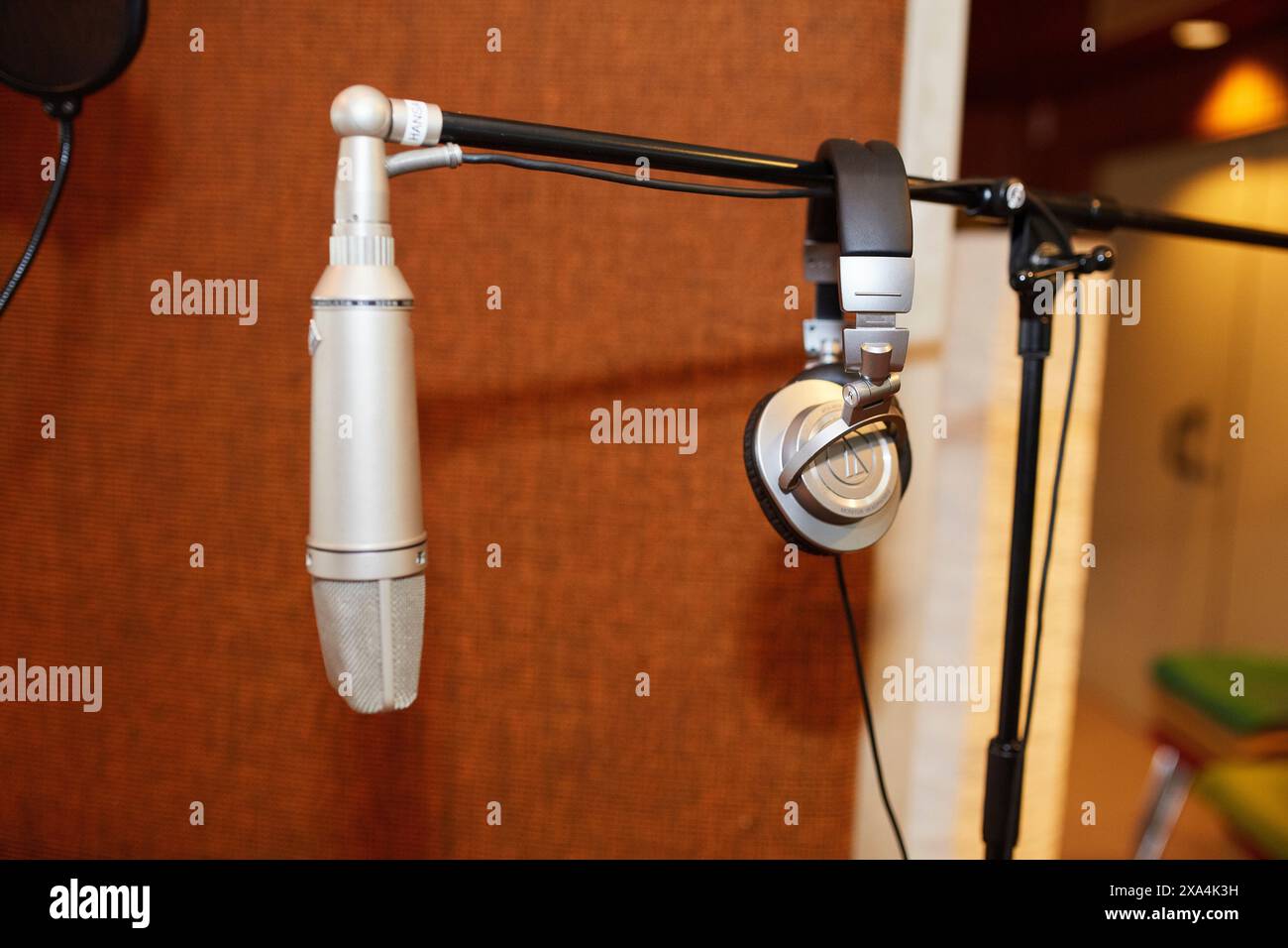 Il microfono da studio e le cuffie sono montati su supporti su uno sfondo sfocato con toni caldi. Foto Stock