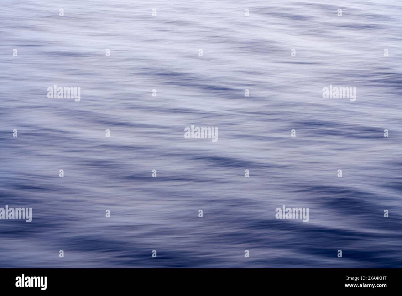 Si tratta di un'immagine tranquilla che mostra la superficie liscia e fluente dell'acqua in sfumature di blu, catturando il delicato movimento delle onde. Foto Stock