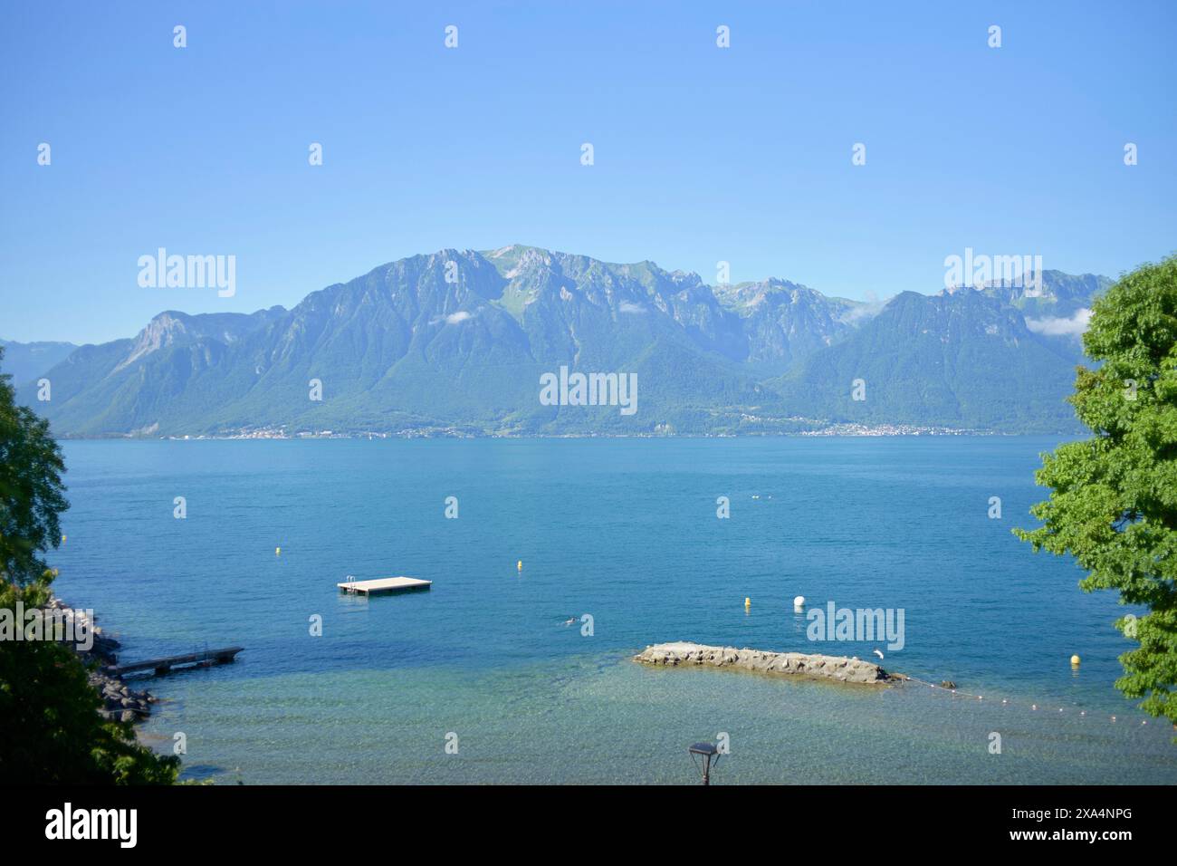 Una vista tranquilla e pittoresca di un lago di montagna con vegetazione lussureggiante in una giornata di sole limpido. Foto Stock