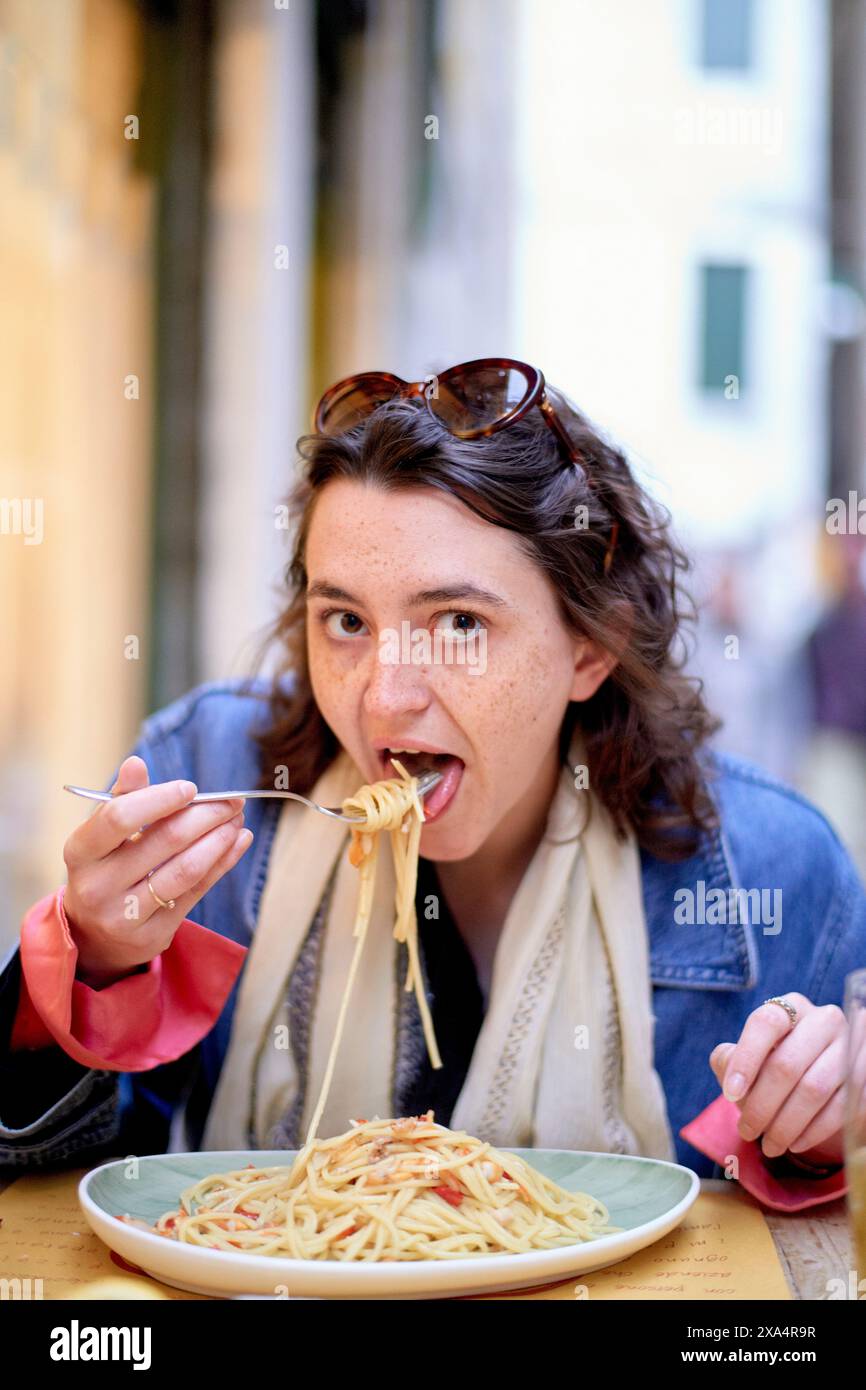 Donna che si gode un piatto di spaghetti in un ambiente all'aperto Foto Stock