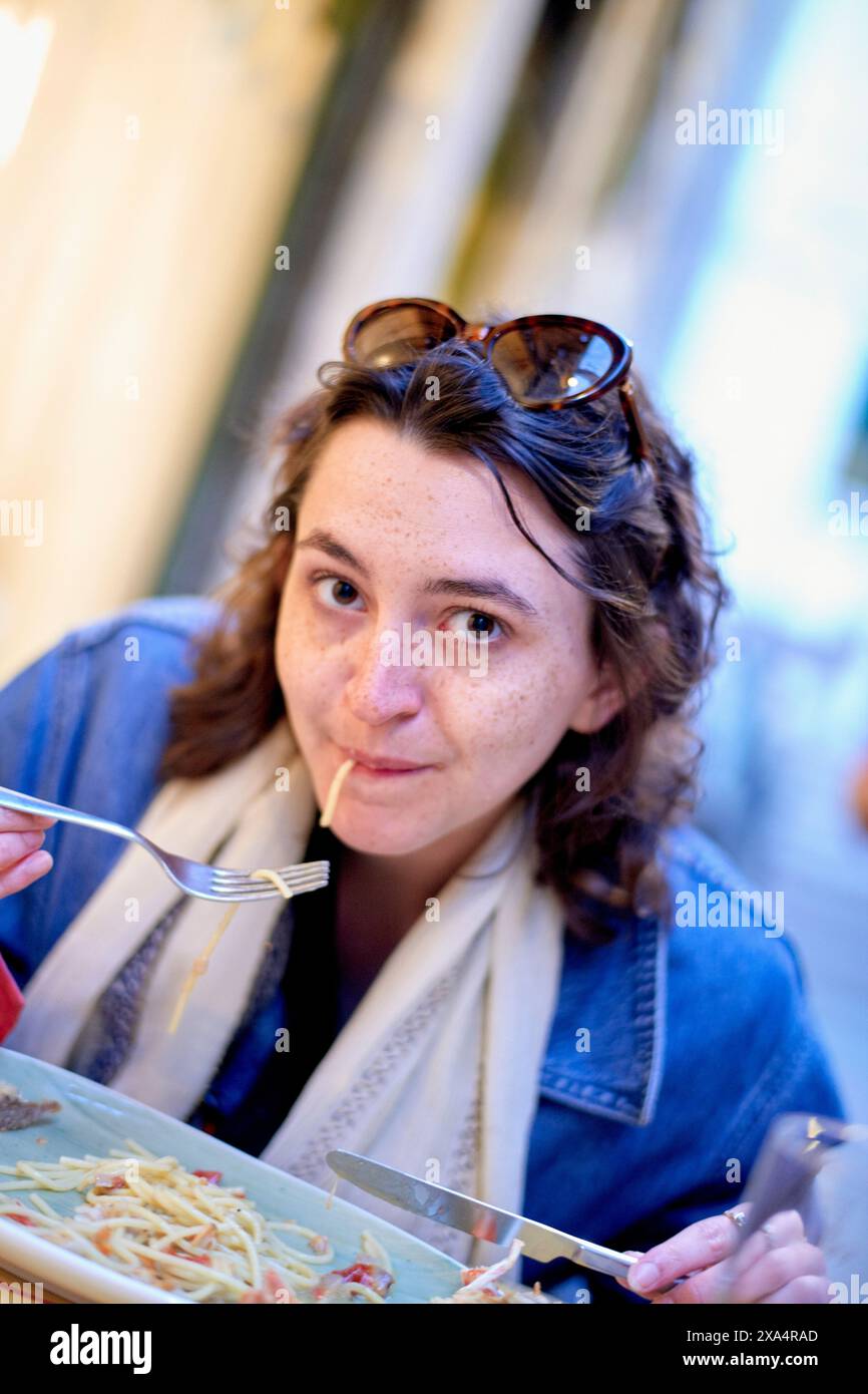 Donna che gusta la pasta in un accogliente ristorante all'aperto Foto Stock